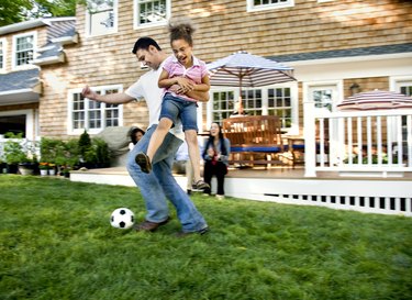 Father playing soccer with daughter in backyard