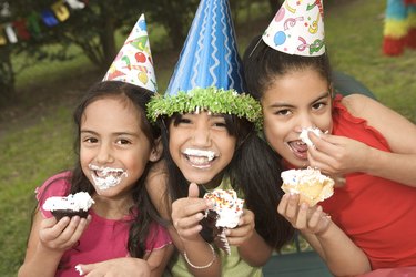 Girls with messy birthday cake at party outdoors