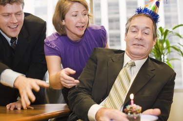 Co-workers and businessman with party hat and cupcake