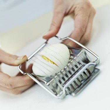 Close-up of a hard boiled egg being sliced in a slicer