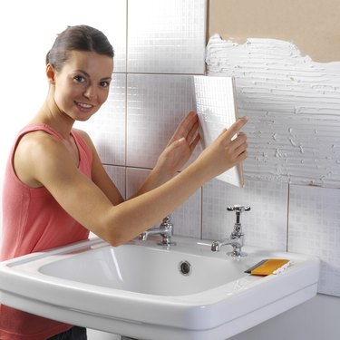 Woman tiling bathroom wall