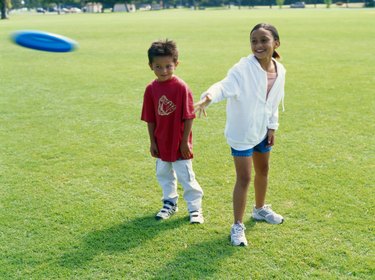 Boy (3-5) and girl (4-7) playing with flying disc