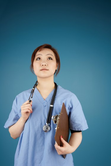 Portrait of female nurse wearing red scrub writing with marker on