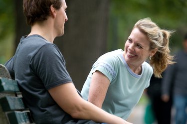 Smiling couple conversing on park bench
