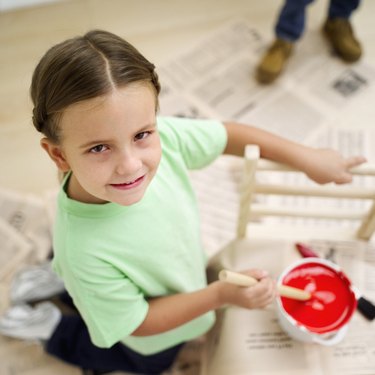 High angle view of a girl stirring a bucket of red paint