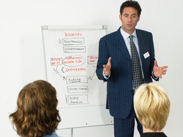 Businessman giving presentation, colleagues in foreground