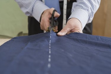 Tailor cutting fabric with scissors