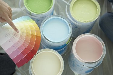 Hand pointing to paint colors above paint cans