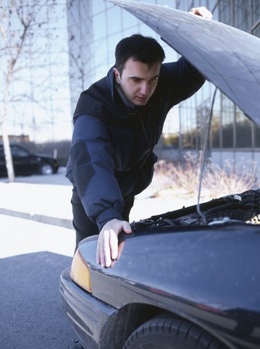 Man looking under the hood of car