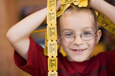 Smiling boy with handful of tickets on his head