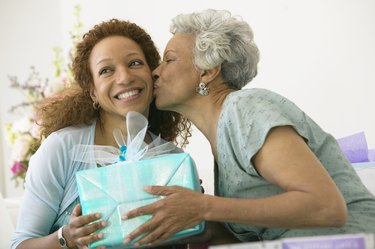 Mother kissing adult daughter, holding present