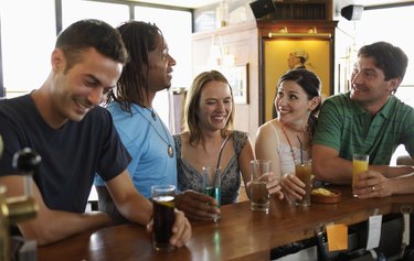 Group of friends standing at bar, smiling