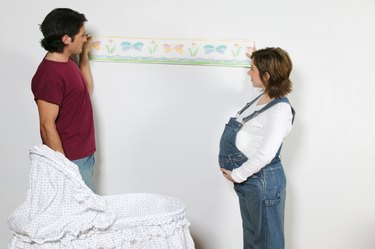 Pregnant couple decorating nursery