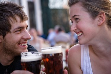 Young woman and man toasting beers outdoors