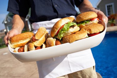 Man holding tray piled with hot dogs and hamburgers