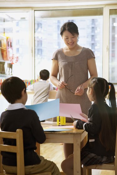 Teacher talking to students doing art in classroom