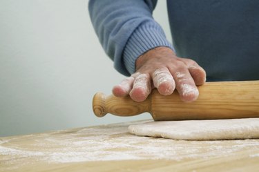 Man preparing dough with rolling pin, close-up