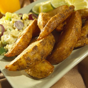 Close-up of potato wedges with scrambled eggs on a tray