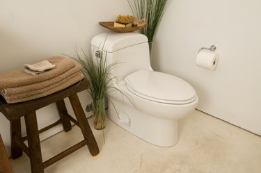 Corner of bathroom with toilet and towels on stool