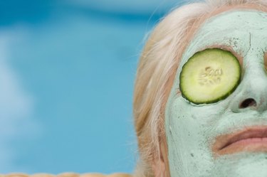 Woman in mud mask with cucumbers