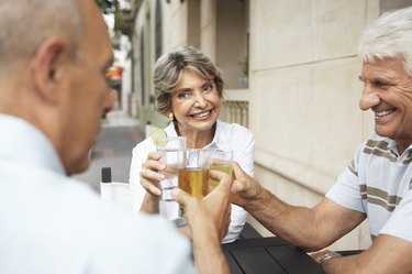 Senior woman and two senior men raising glasses, outdoors, close-up