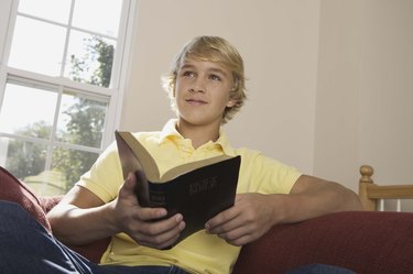 Boy holding Holy Bible indoors