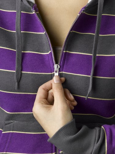 Young woman zipping purple hooded sweatshirt, close-up (full frame)