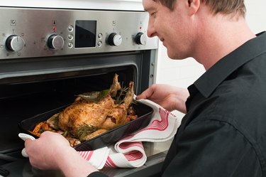 Man roasting chicken in oven