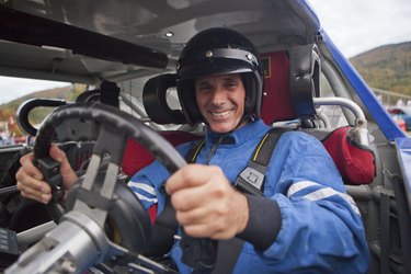 Disabled race car driver with spinal cord injury in a modified car with removable steering wheel, gas and brake hand controls and push button automatic transmission