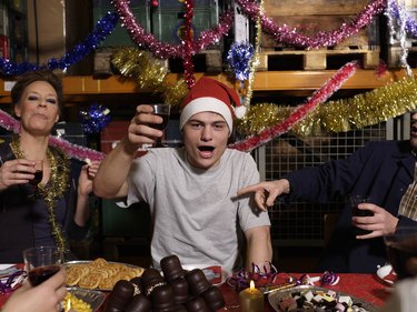 Group of workers toasting with wine glasses at Christmas table in warehouse, portrait