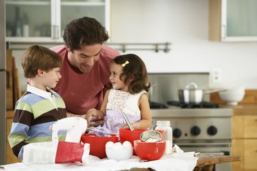 Father, son (5-7) and daughter (2-4) baking in kitchen