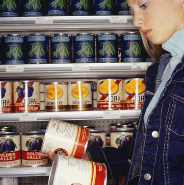 Teenage girl (16-17) looking at canned peaches