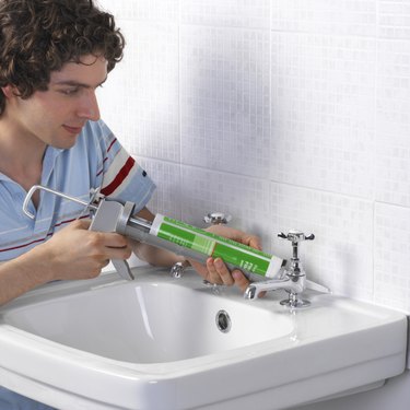 Man using caulking gun on sink