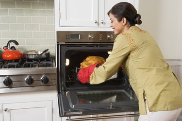 Woman taking Thanksgiving turkey out of oven