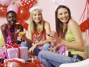 Three young women looking away from camera with drinks at party