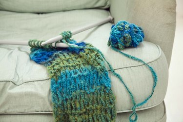 Knitting needles and scarf on chair