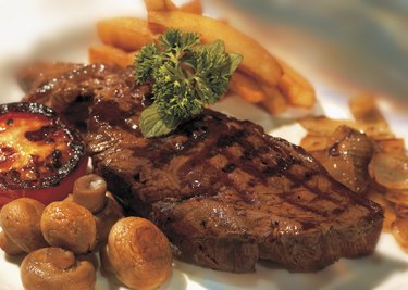 close-up of a piece of grilled meat served with vegetables and fries