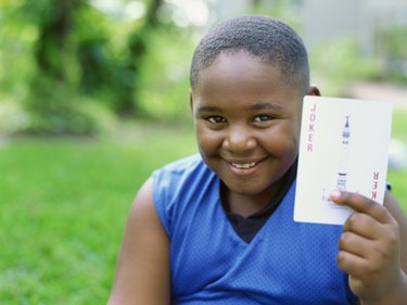 Portrait of a boy holding a joker card