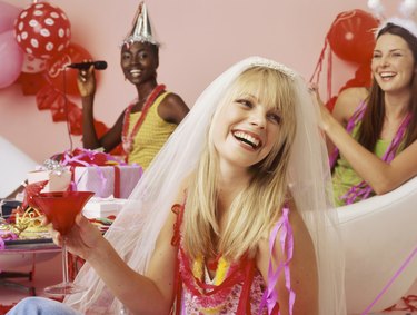 Three young women smiling with drinks at hen party