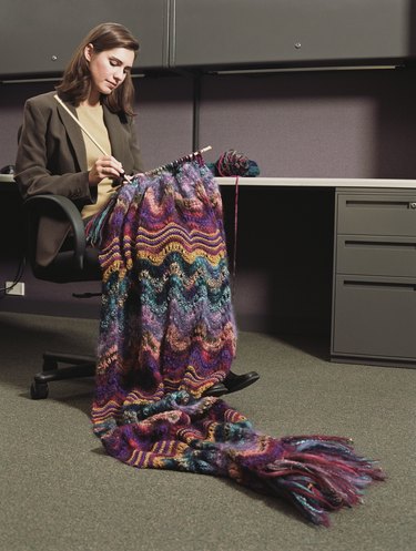 Businesswoman sitting at a desk knitting