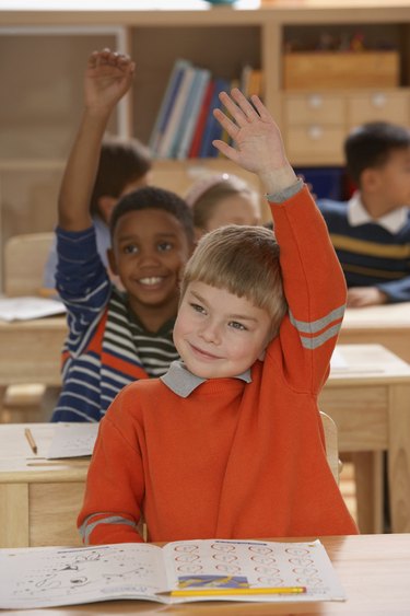 Close-up of a boy raising his hand in a classroom