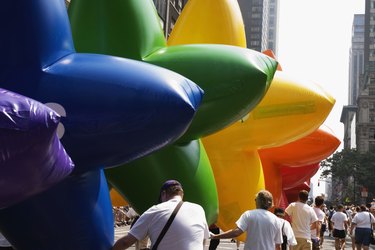 Row of men holding large rainbow-colored, star-shaped balloons, close-up