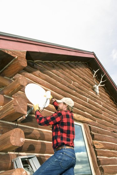 Man installing satellite dish on house