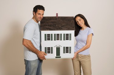 Woman and man holding miniature house