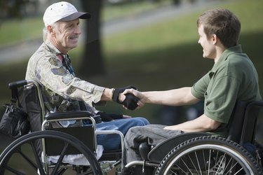 Side profile of a mature war veteran shaking hands with a young man