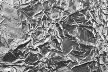Abstract crumpled silver aluminum foil closeup background texture, grey horizontal