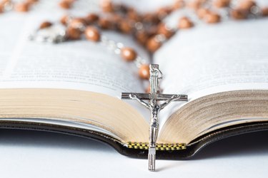 Cross of rosary beads resting against bible