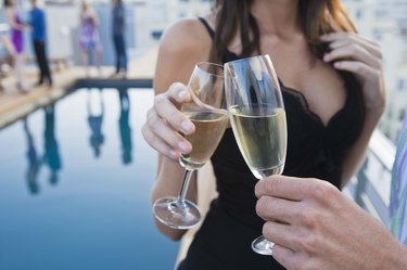 Couple toasting champagne poolside