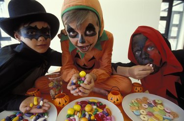 Kids dressed in Halloween costumes eating candy