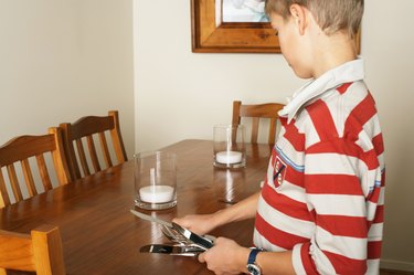 Boy (10-12) laying table with cutlery, side view